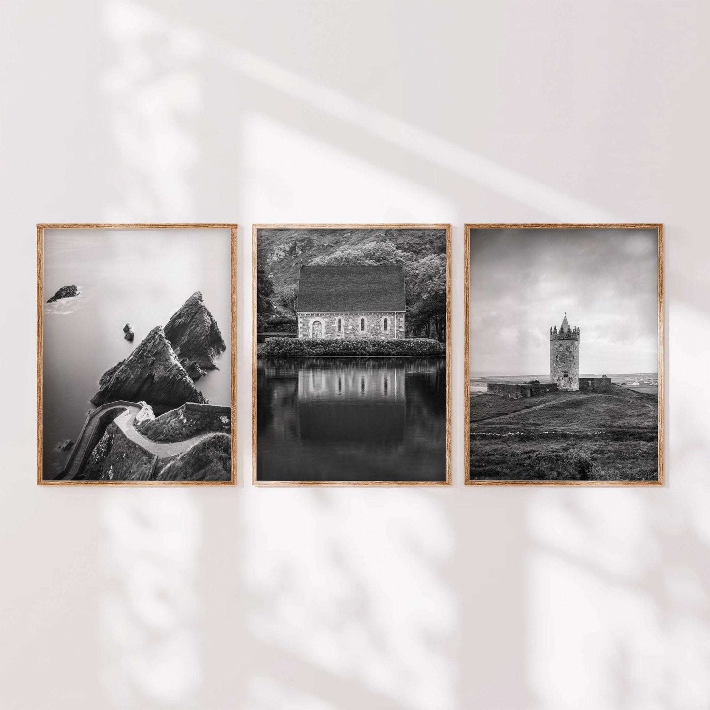 Minimalist display of three black and white Irish landscape prints in wooden frames arranged side by side.
