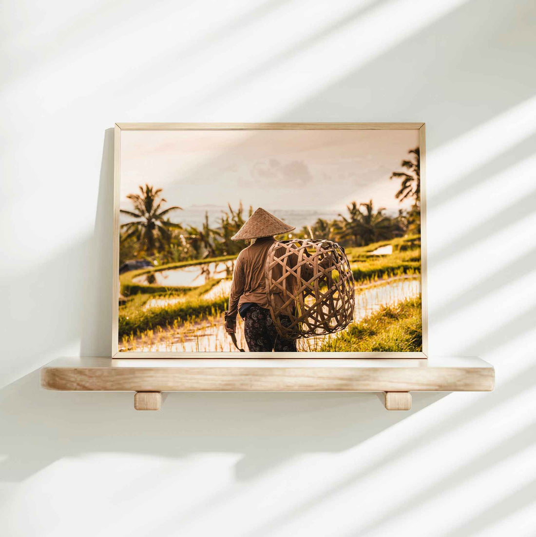 Gold framed print of a Balinese farmer at Jatiluwih Rice Terraces Bali on a minimalist wall shelf with soft natural light