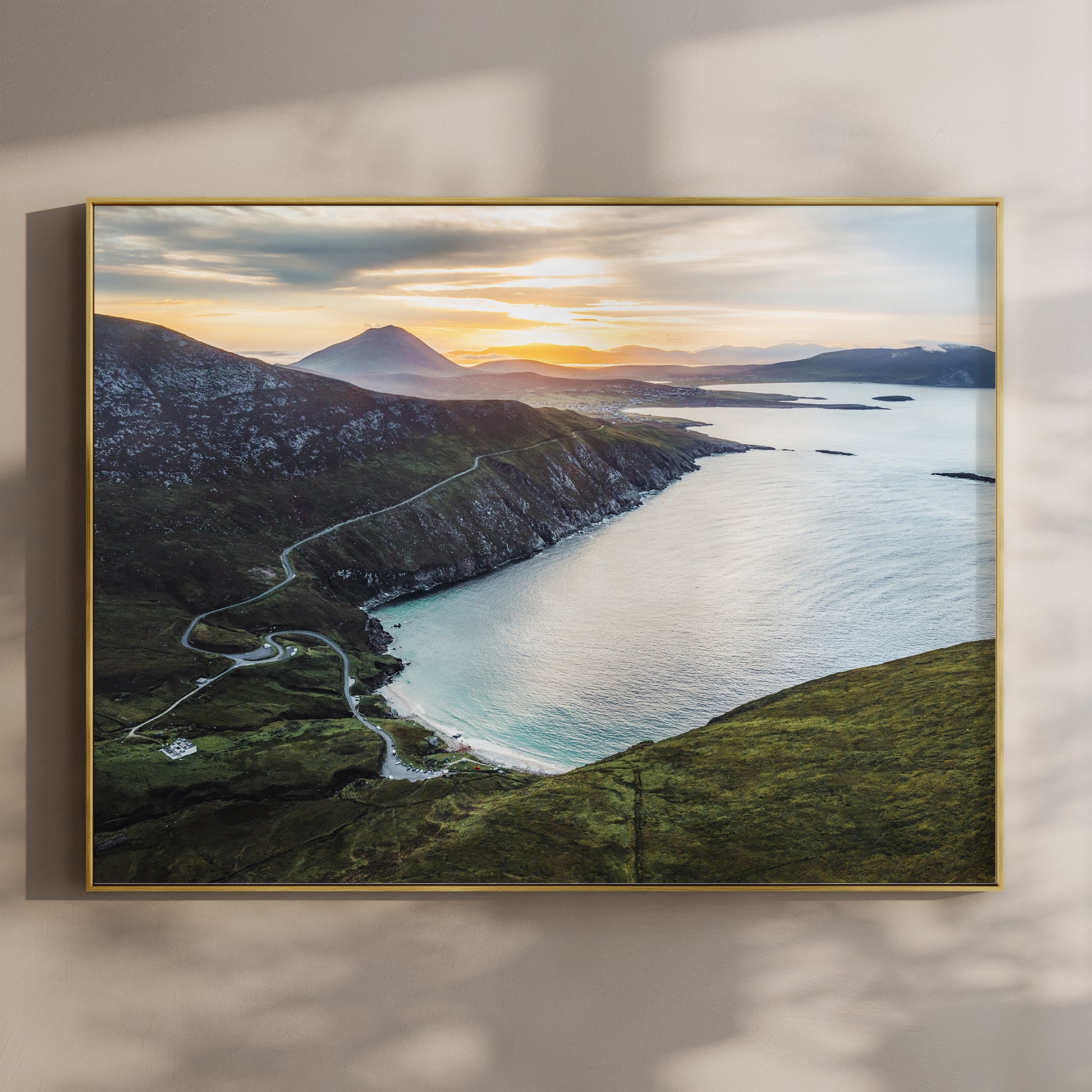 Aerial view of Keem Beach at sunset on Achill Island with winding coastal road and golden light
