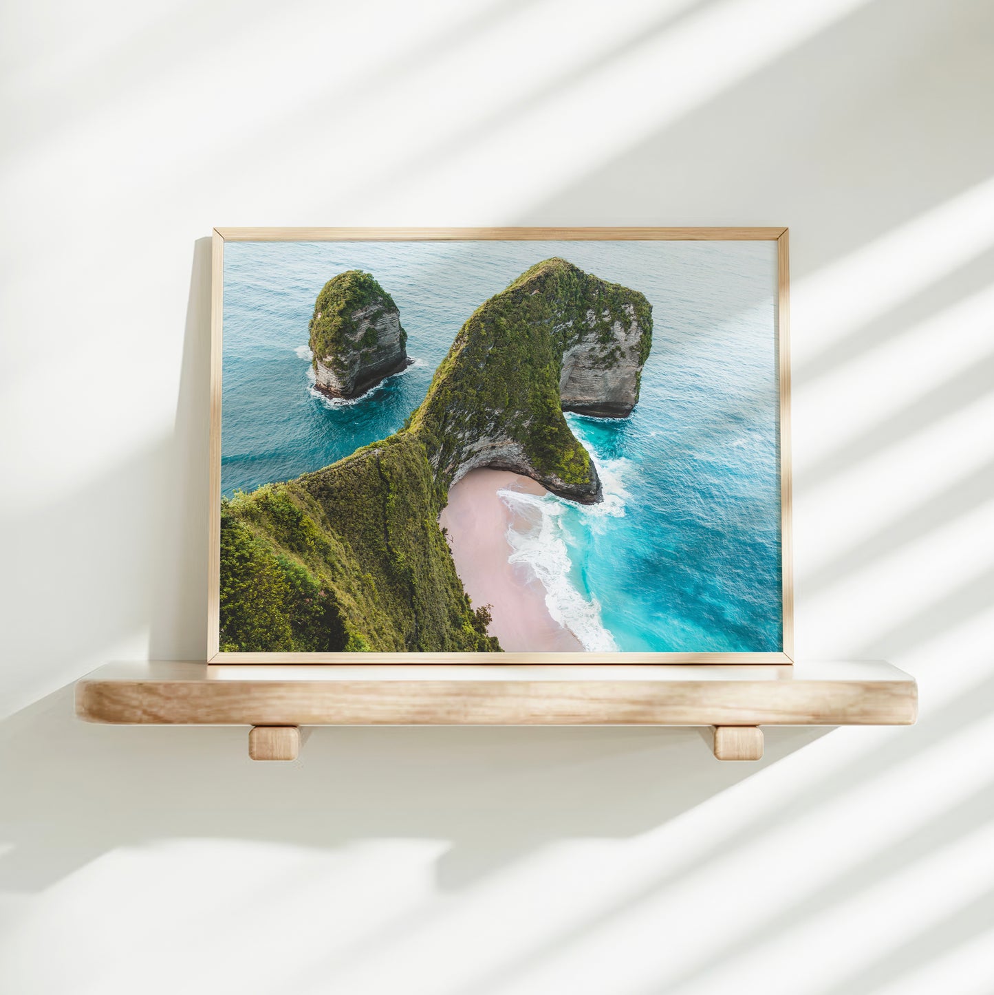 Gold framed aerial print of Kelingking Beach Nusa Penida Bali on a minimalist wall shelf with soft natural light