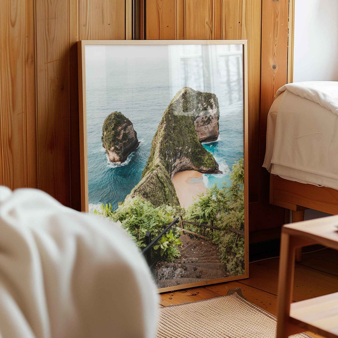 print-natural-wood-frame-bedroomKelingking Beach Nusa Penida framed photography print leaning against wooden wall in cozy bedroom interior
