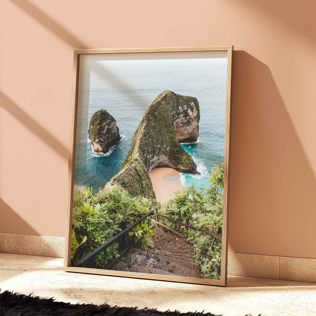 Kelingking Beach Nusa Penida travel print in natural wood frame leaning against peach terracotta wall