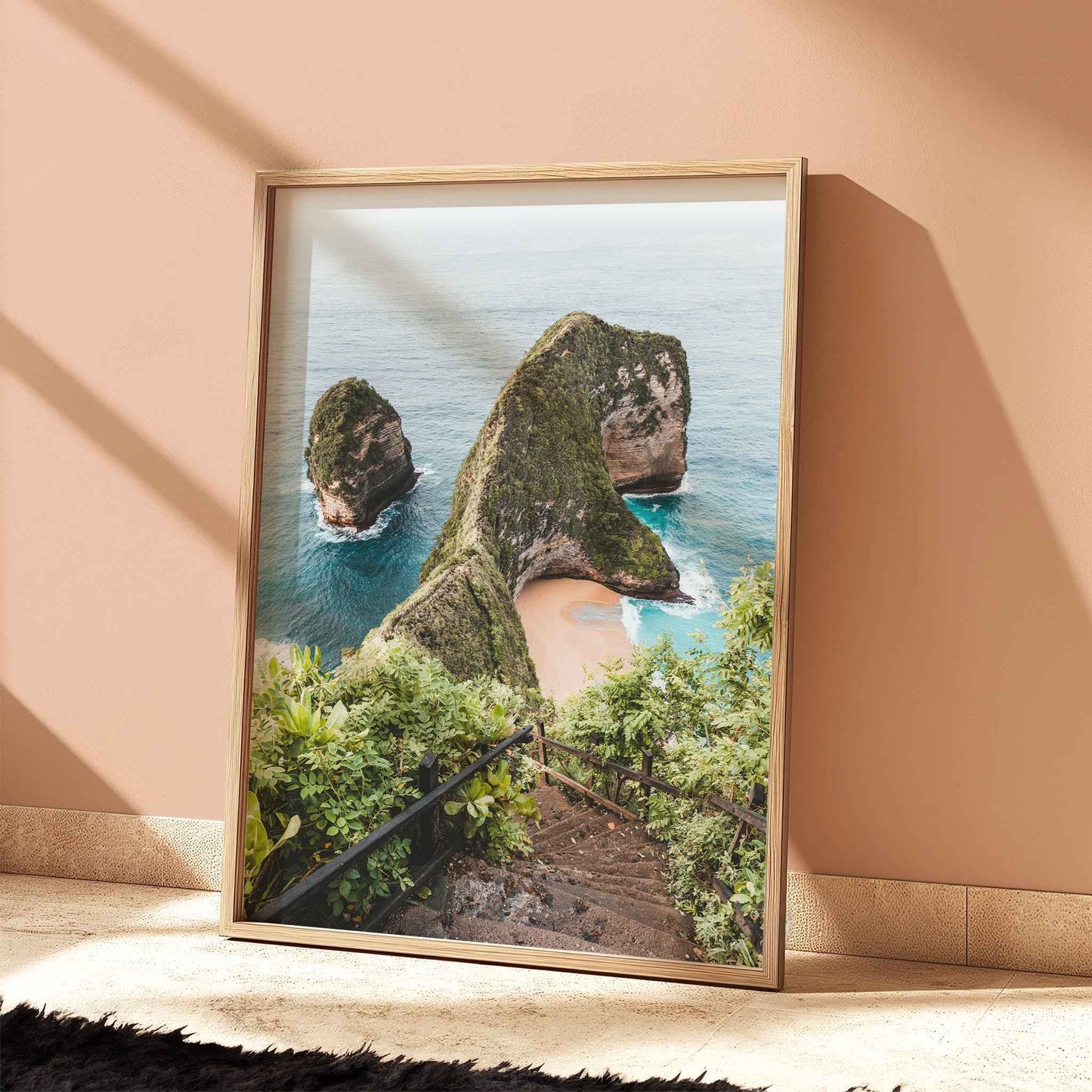 Kelingking Beach Nusa Penida travel print in natural wood frame leaning against peach terracotta wall