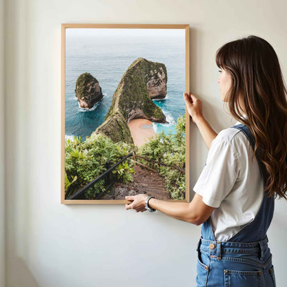 Woman hanging Kelingking Beach Nusa Penida framed art print in natural oak wood frame on white wall