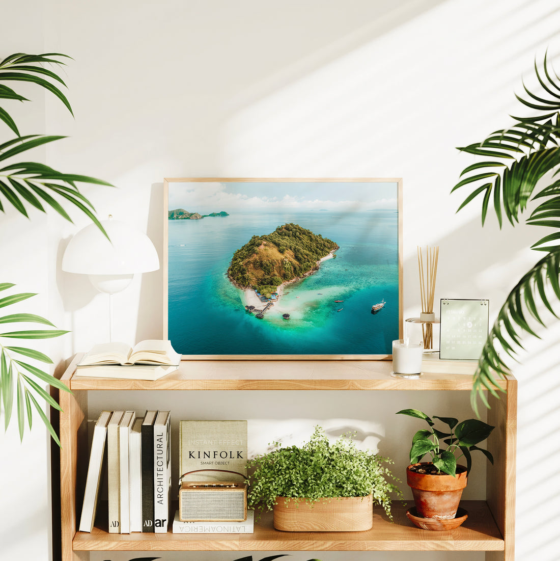 Framed Kelor Island Komodo aerial print styled on a bookshelf in a bright living room interior