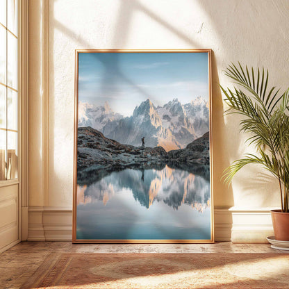 A lone hiker by the shores of Lac Blanc, with the Aiguilles de Chamonix mirrored in the tranquil water at sunset.
