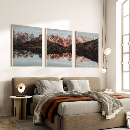 Set of three Lac Blanc wall art prints displayed above a bed in a modern, cozy bedroom.