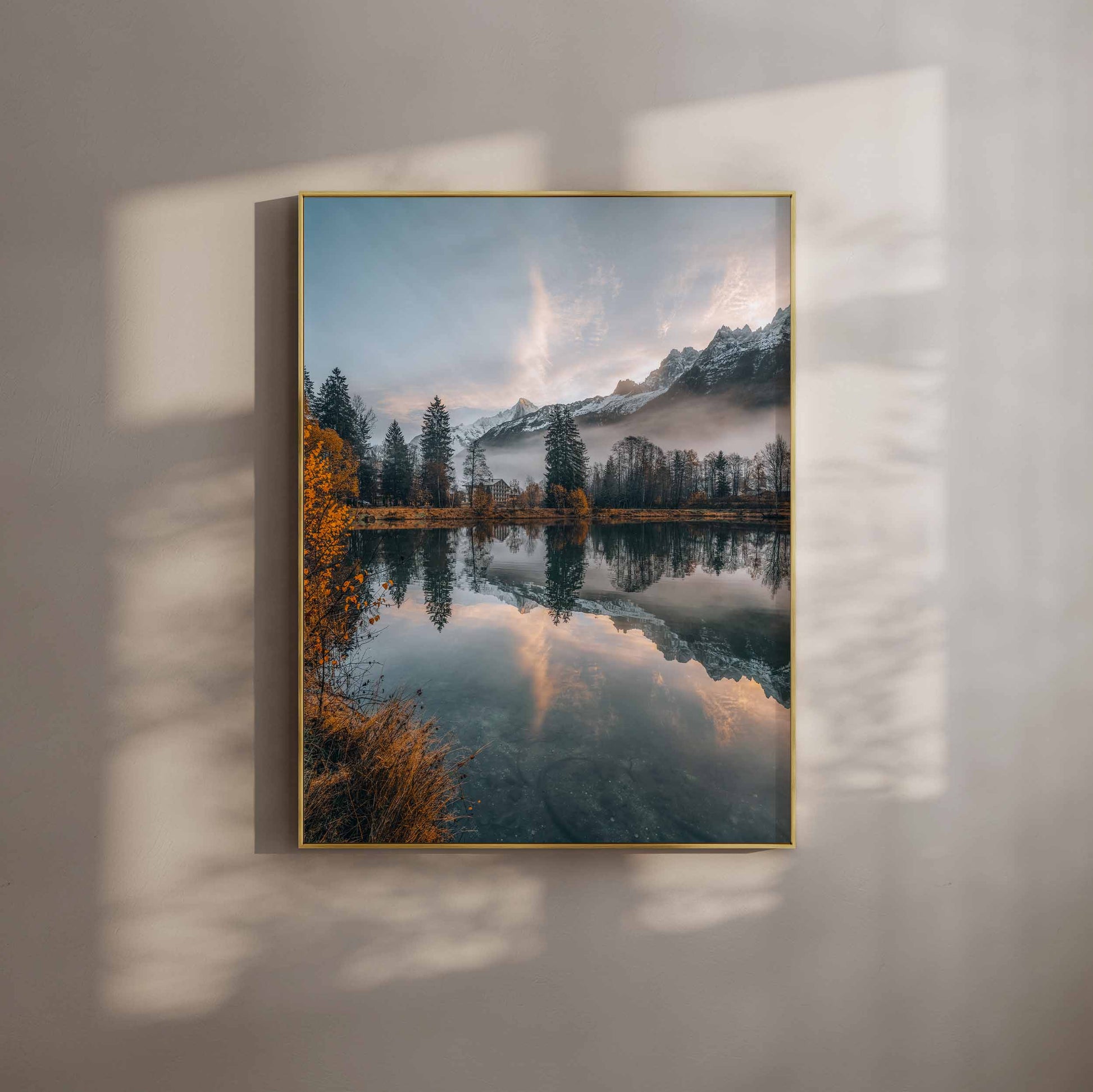 Lac des Gaillands at sunrise in autumn, reflecting golden hues and misty mountains in Chamonix, with a gold frame.