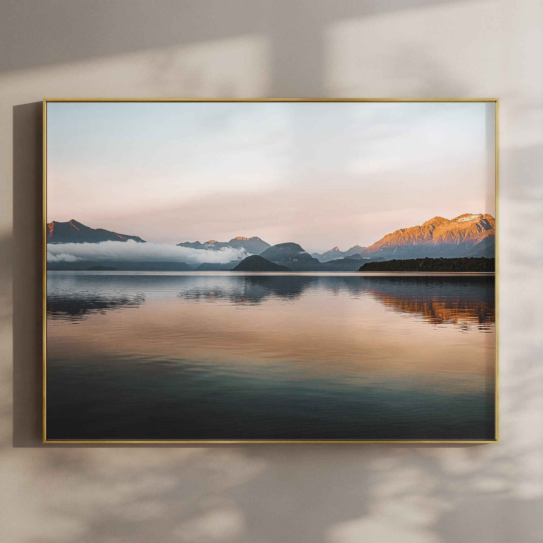 Lake Manapouri New Zealand photography print in gold float frame mounted on warm beige wall with window light shadows