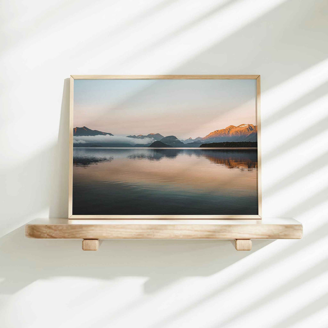 Lake Manapouri New Zealand landscape photography print in natural wood frame on floating shelf against white wall with light shadows