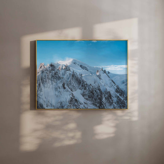 Framed print of Massif du Mont Blanc against a clear blue sky, displayed with soft natural shadows.