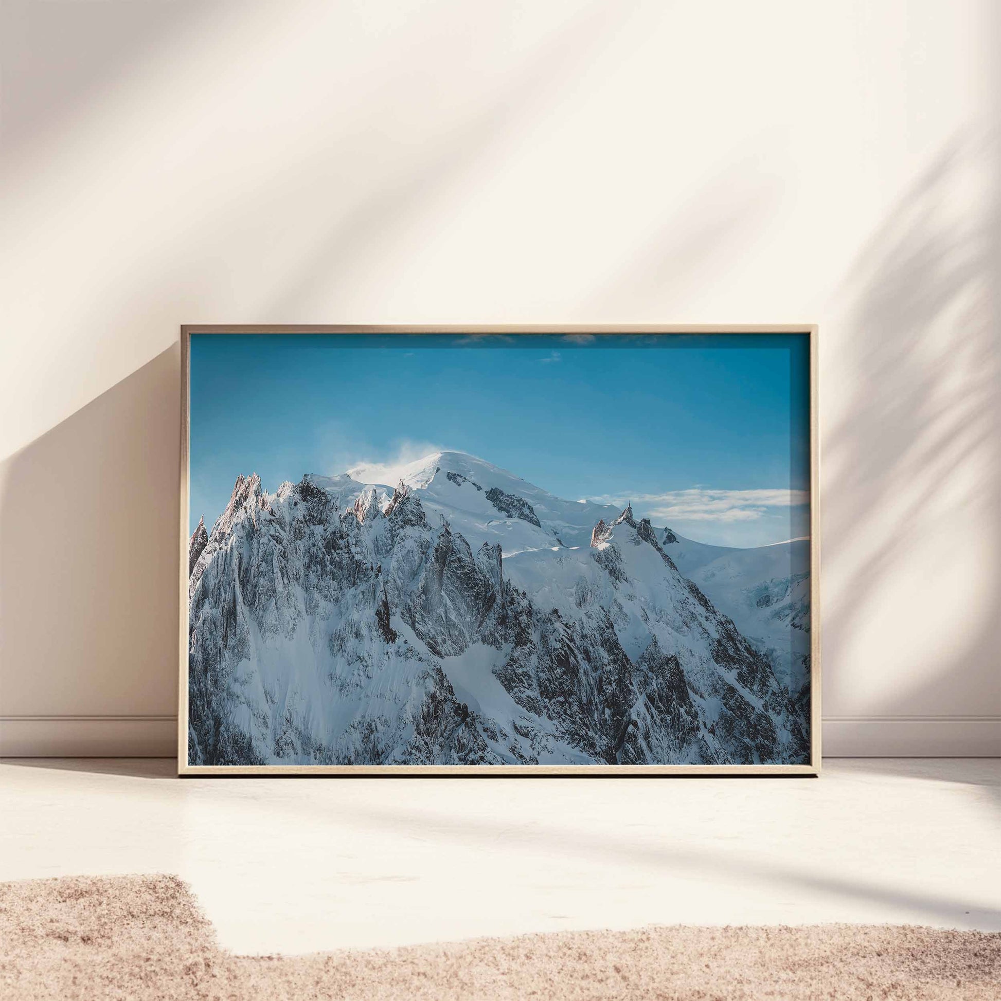 Horizontal framed print of Massif du Mont Blanc resting on the floor in bright natural lighting.