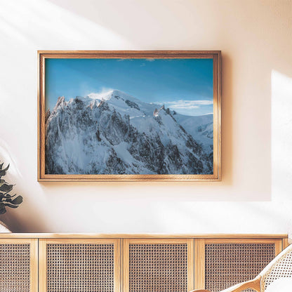 Massif du Mont Blanc artwork in a wooden frame, hung on a textured wall above a wooden sideboard.