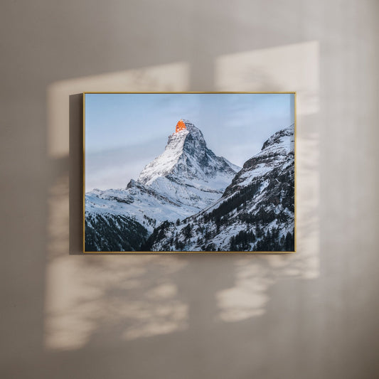 Matterhorn mountain covered in snow with the peak glowing orange at sunset.