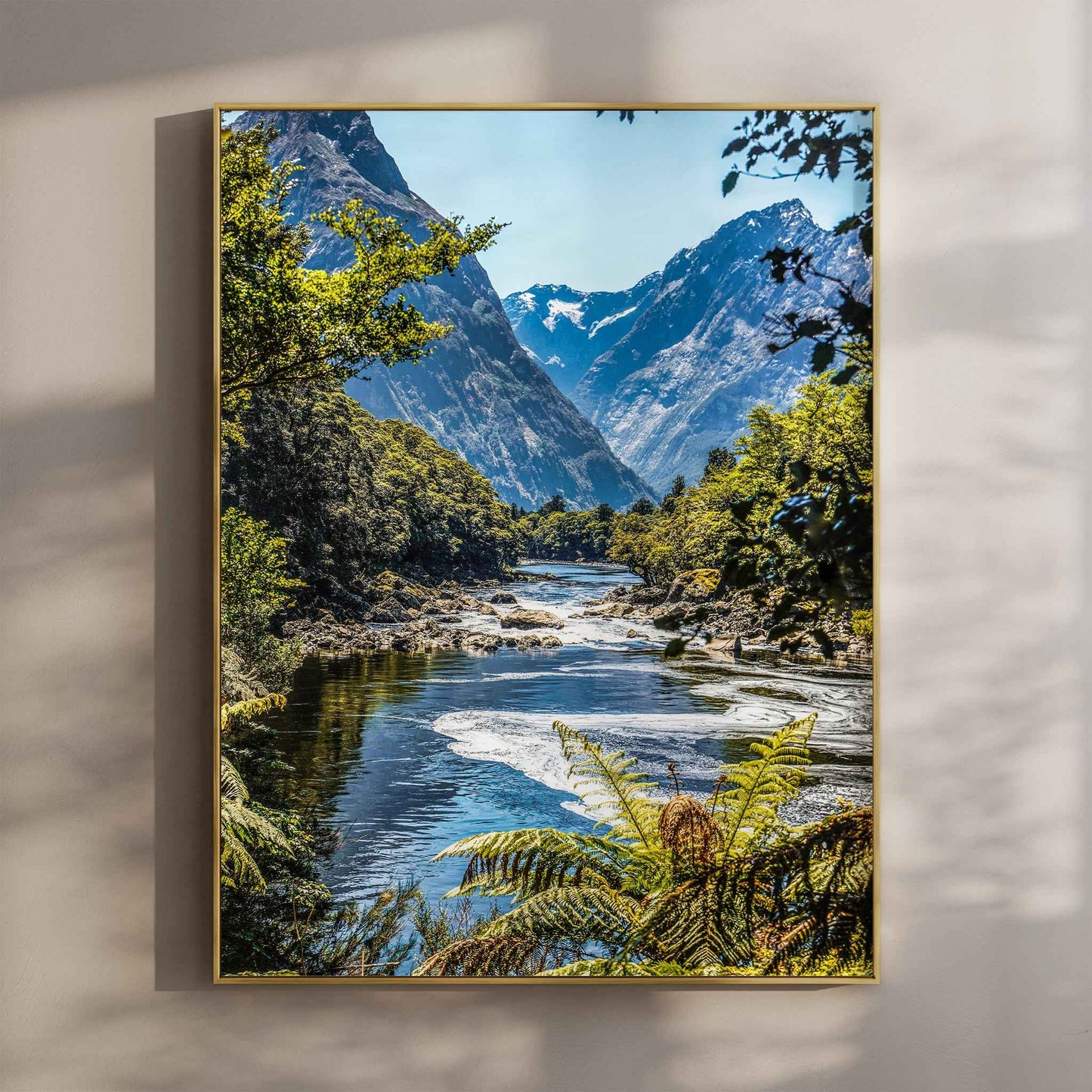 Framed print of Milford Track Fiordland New Zealand river and mountains in a gold float frame mounted on a wall
