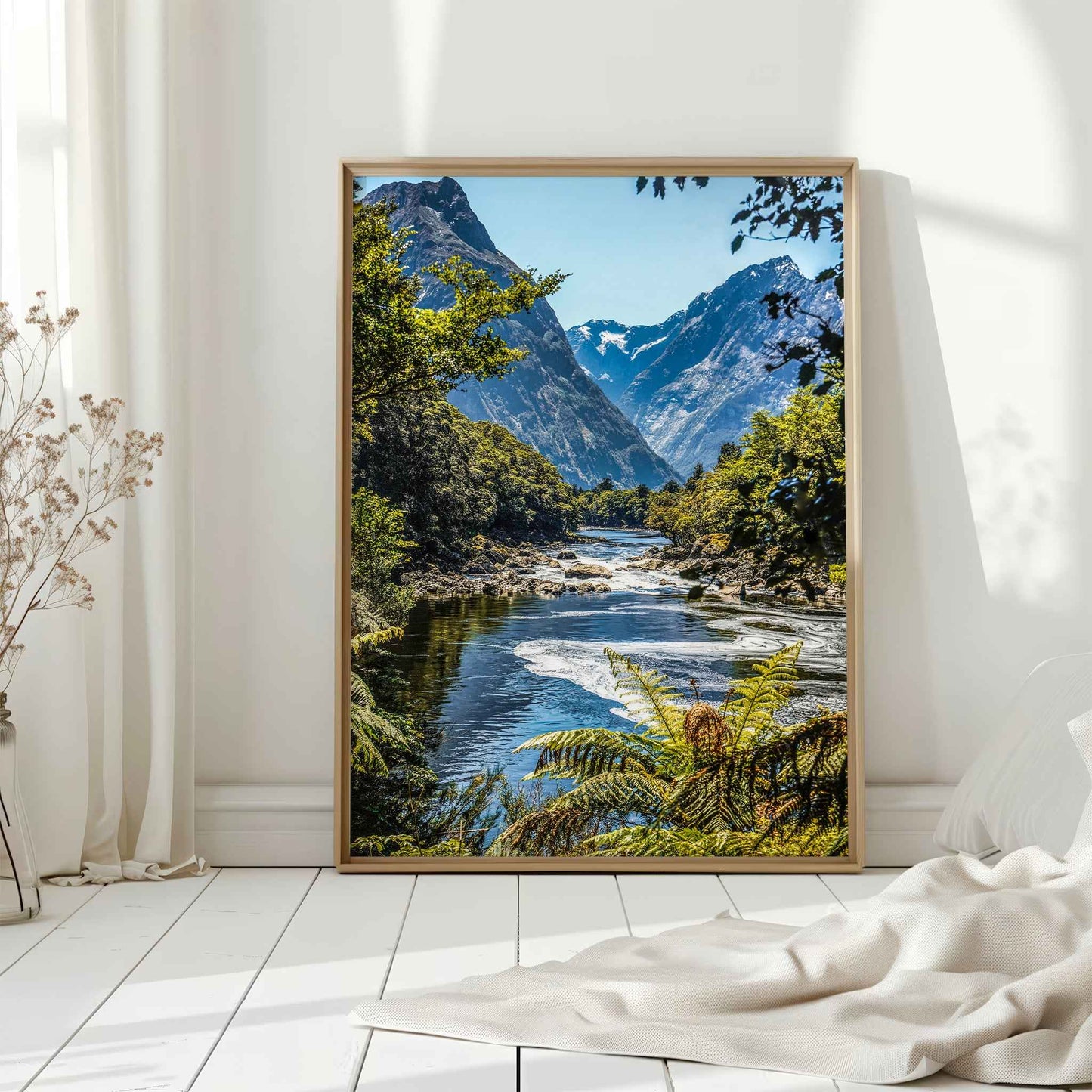 Natural wood framed Milford Track Fiordland New Zealand print leaning against a white wall in a bright interior