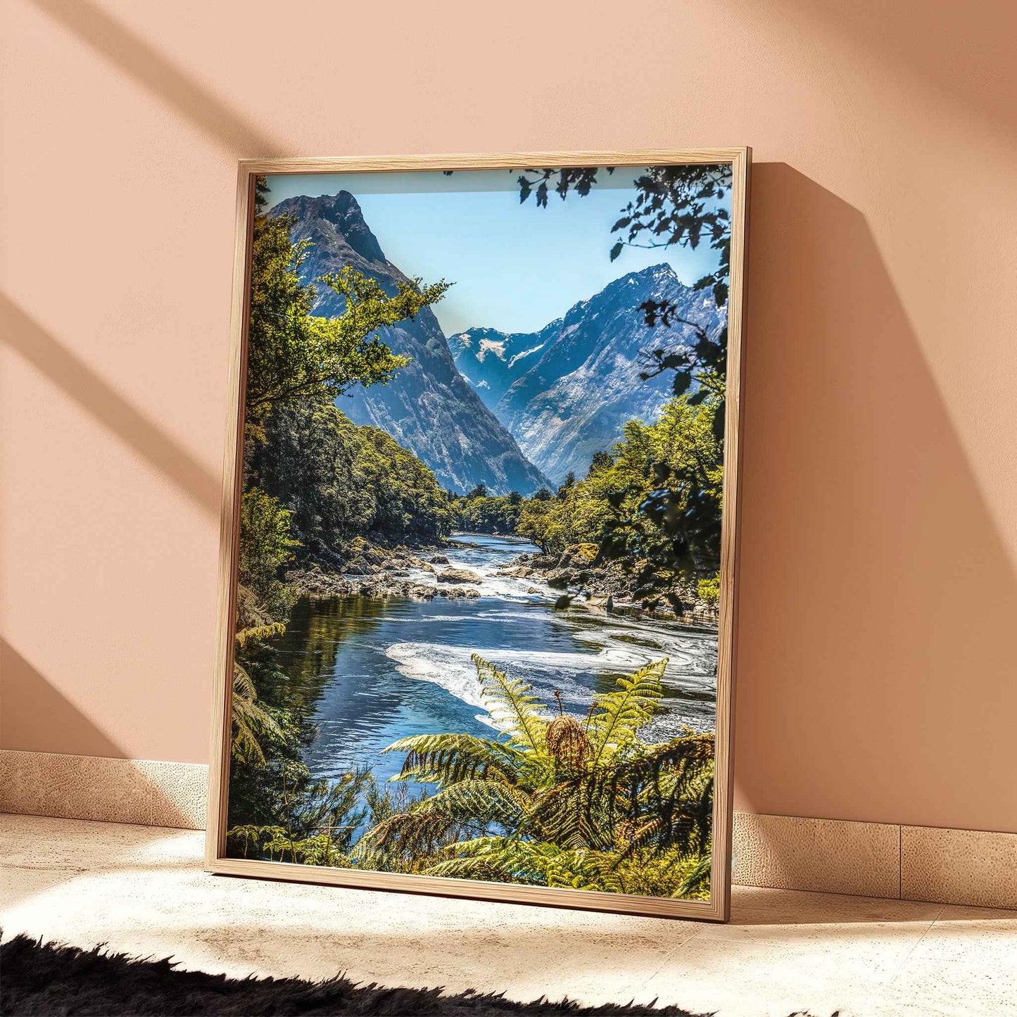 Natural wood framed Milford Track Fiordland New Zealand print leaning against a terracotta wall