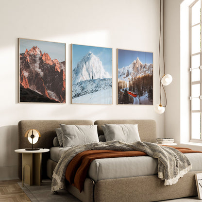 Set of three alpine wall art prints displayed above a bed in a modern bedroom.