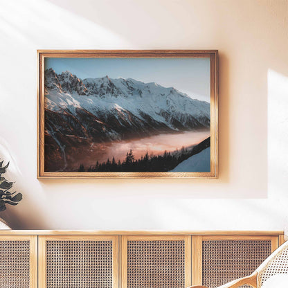 Golden hour Mont Blanc massif print framed in a classic wooden frame on a wall above a rattan cabinet.