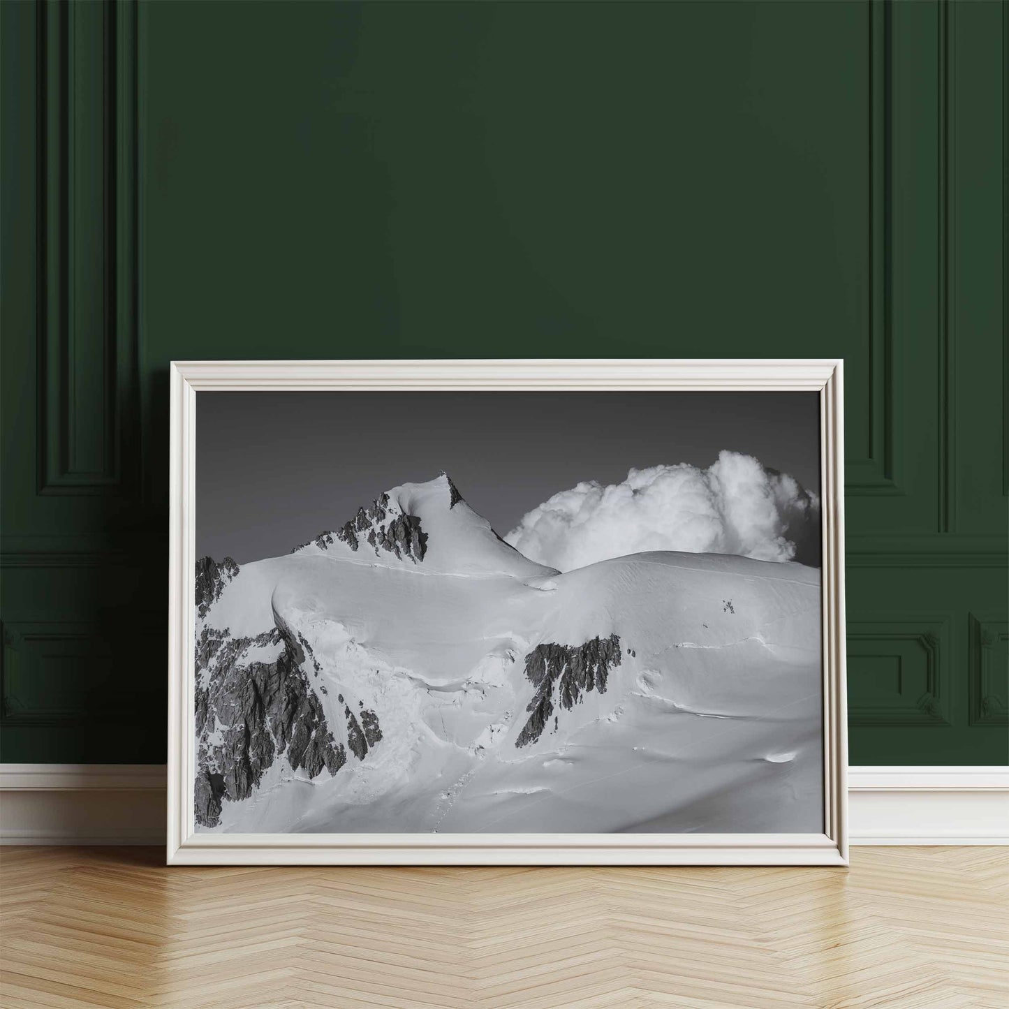 Mont Maudit black and white print resting on the floor against a deep green wall, showcasing alpine scenery.