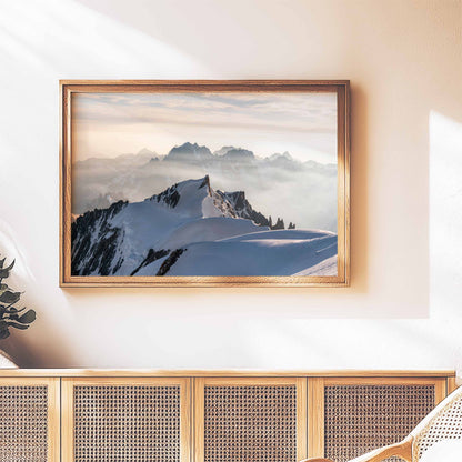 Mont Maudit summit framed art displayed above a wooden cabinet in a bright interior.