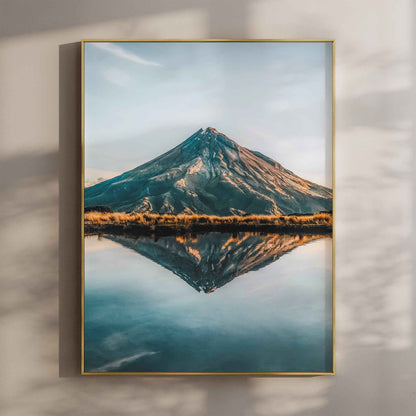 Framed Mount Taranaki reflection photography print in gold float frame mounted on warm beige wall with window light shadows