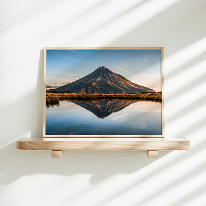 Mount Taranaki volcano reflection tarn landscape photography print in natural wood frame on floating shelf against white wall with light shadows