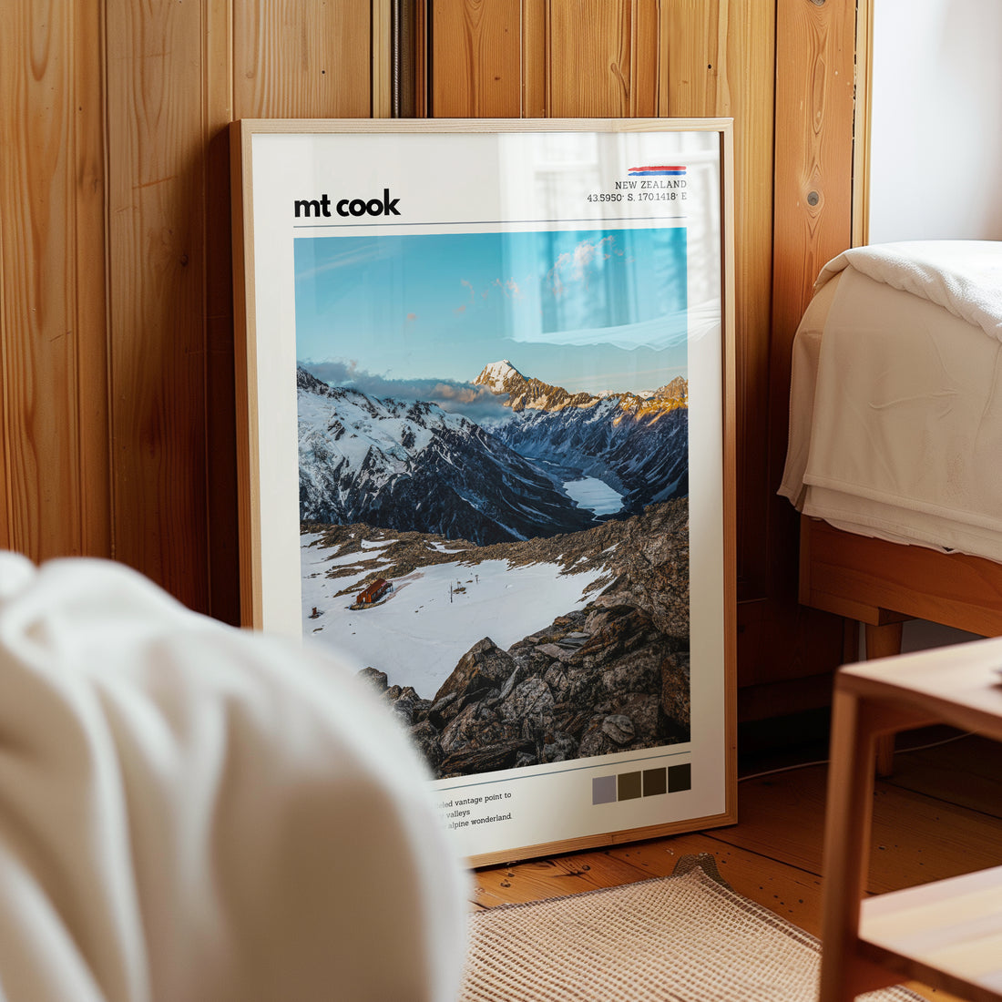 Framed Mt Cook wall art print leaning against a wooden wall in a cozy interior, featuring the alpine landscape near Mueller Hut in Aoraki Mount Cook National Park, New Zealand.