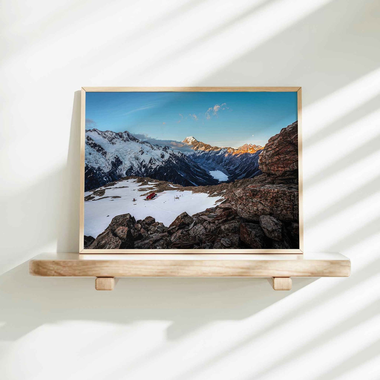 Mueller Hut Mount Cook National Park landscape photography print in natural wood frame on floating shelf against white wall with light shadows