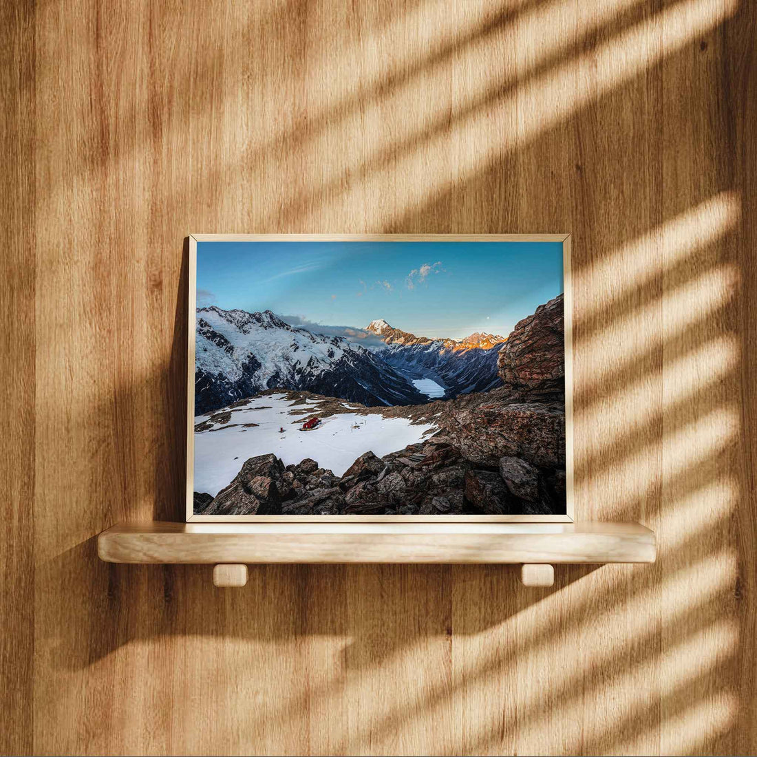 Framed Mueller Hut Mount Cook landscape print in natural wood frame leaning on shelf against warm oak panelled wall