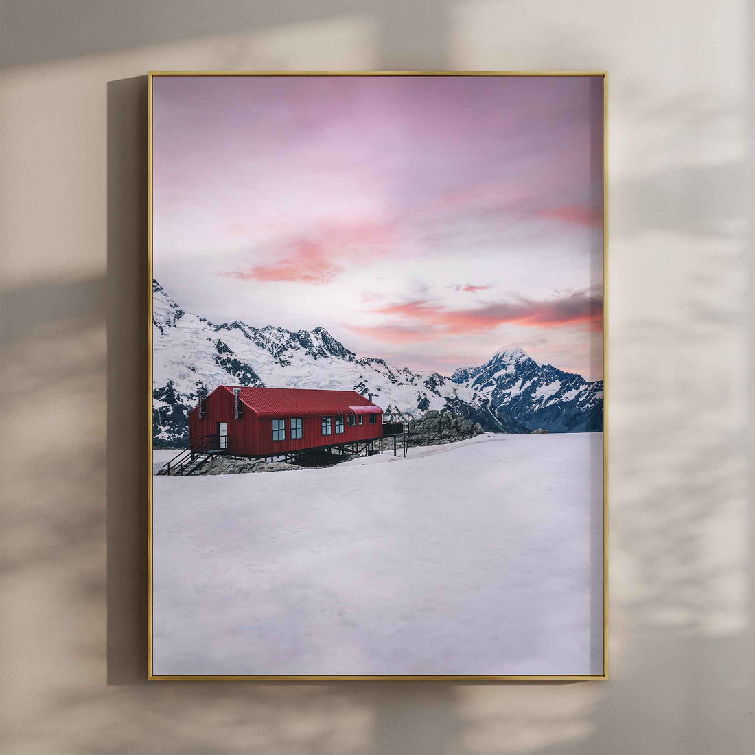 Framed Mueller Hut and Mount Cook winter photography print in gold float frame mounted on warm beige wall with window light shadows