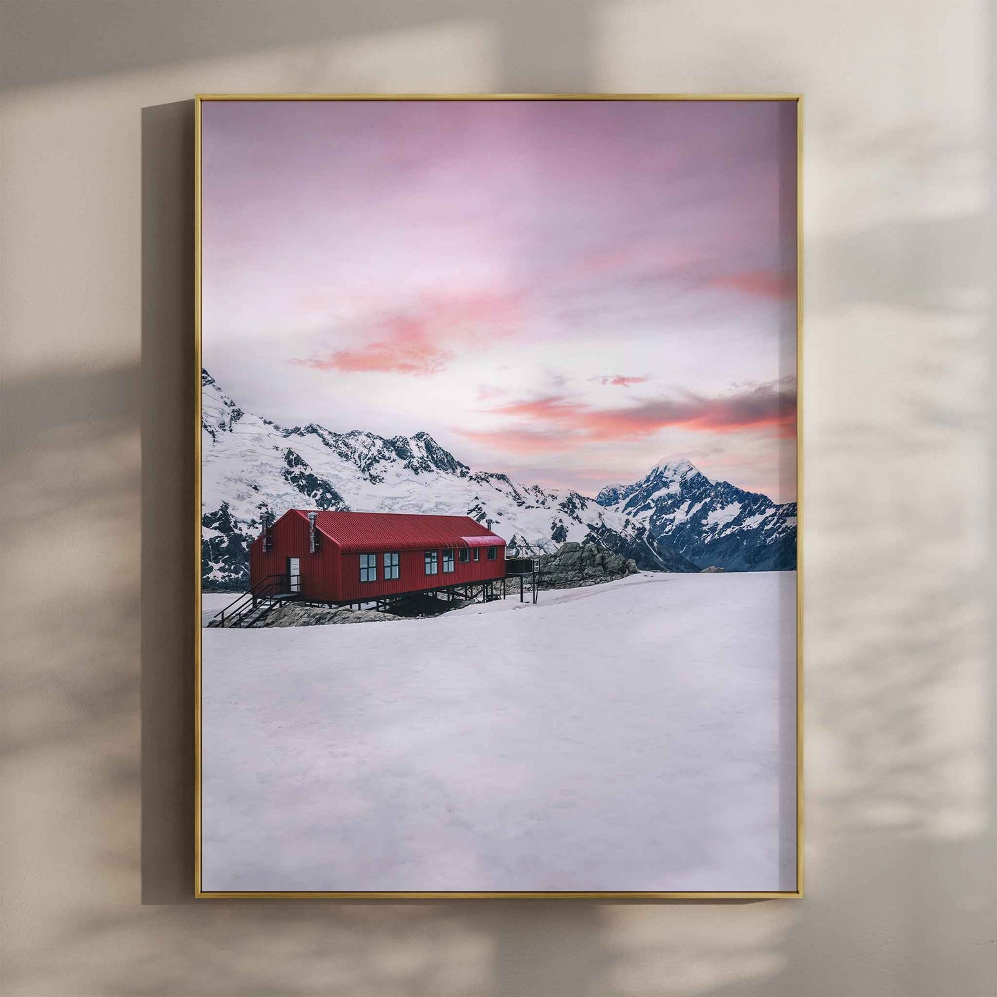 Framed Mueller Hut and Mount Cook winter photography print in gold float frame mounted on warm beige wall with window light shadows