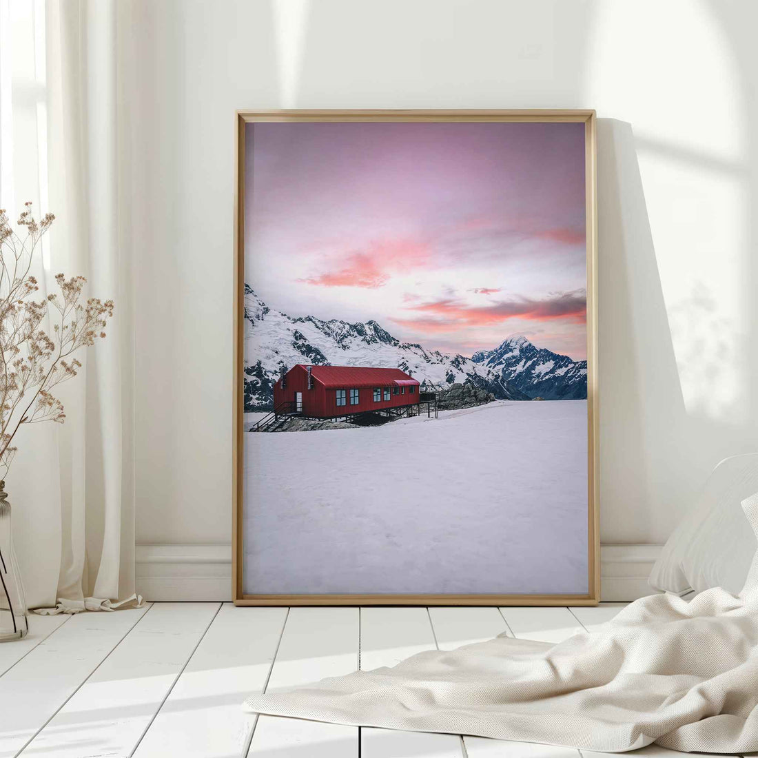Natural wood framed Mueller Hut and Mount Cook winter print leaning against white wall on white floorboards in minimal Scandinavian interior