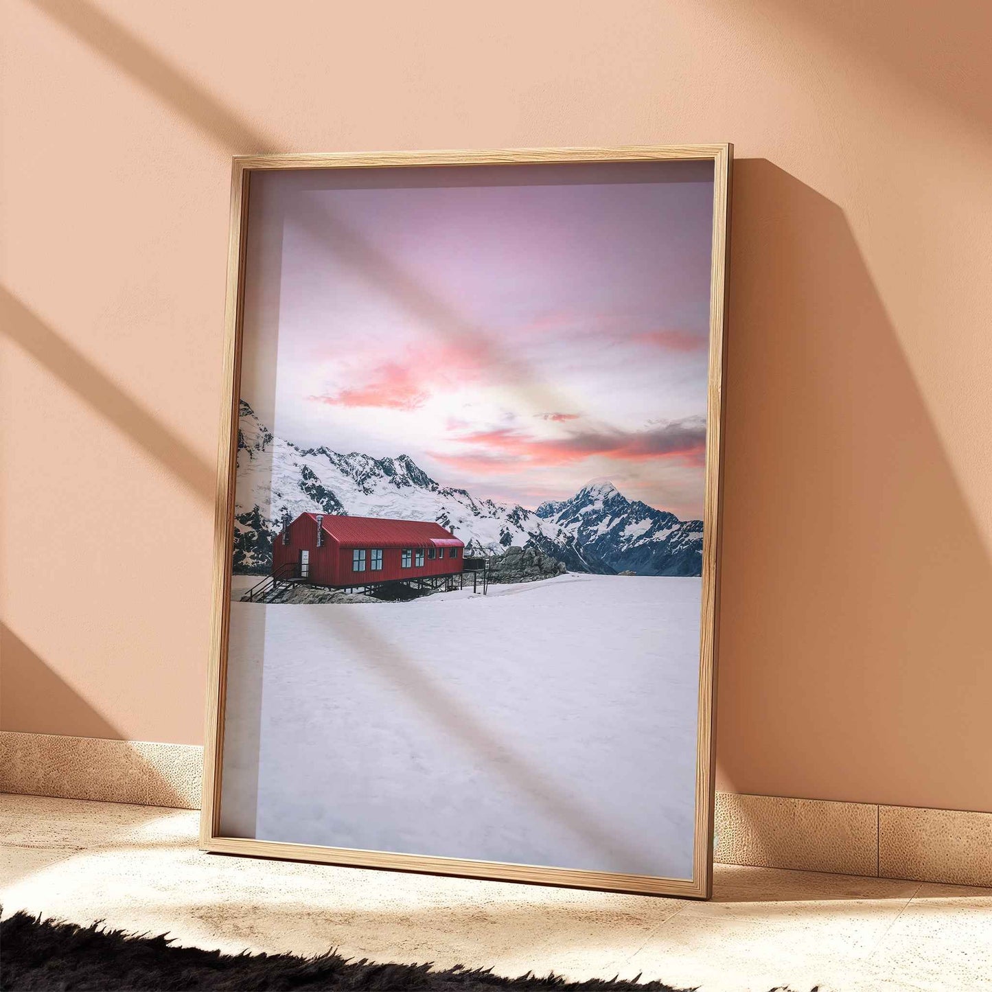 Framed Mueller Hut and Aoraki Mount Cook winter print in light wood frame leaning against terracotta wall with dramatic shadows