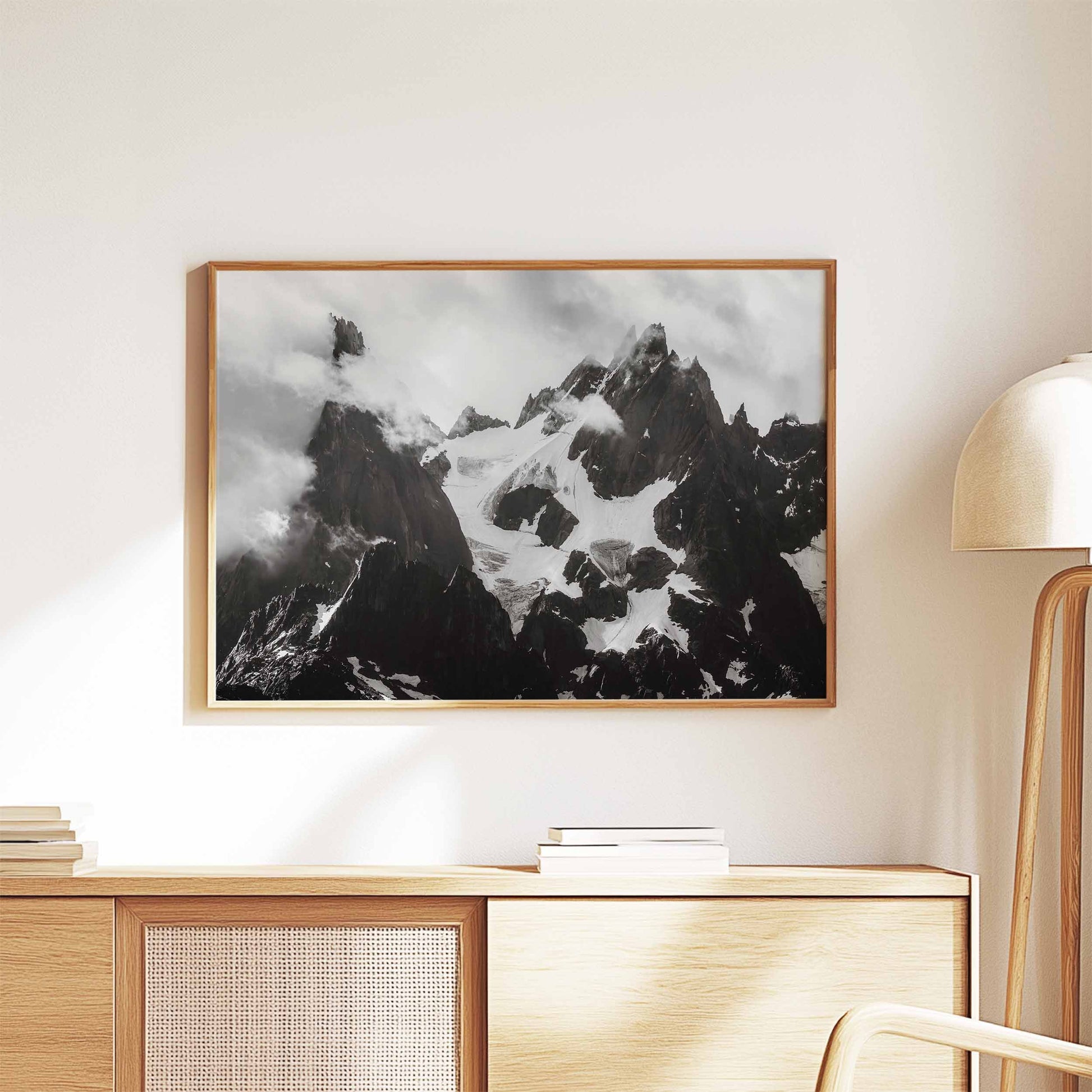 Black-and-white framed print of the Needles of Chamonix on a wooden console table with a modern lamp.