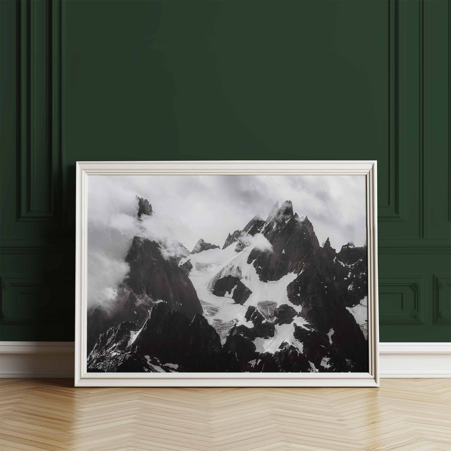 Black-and-white photograph of the Needles of Chamonix, displayed in a white frame against a dark green wall.