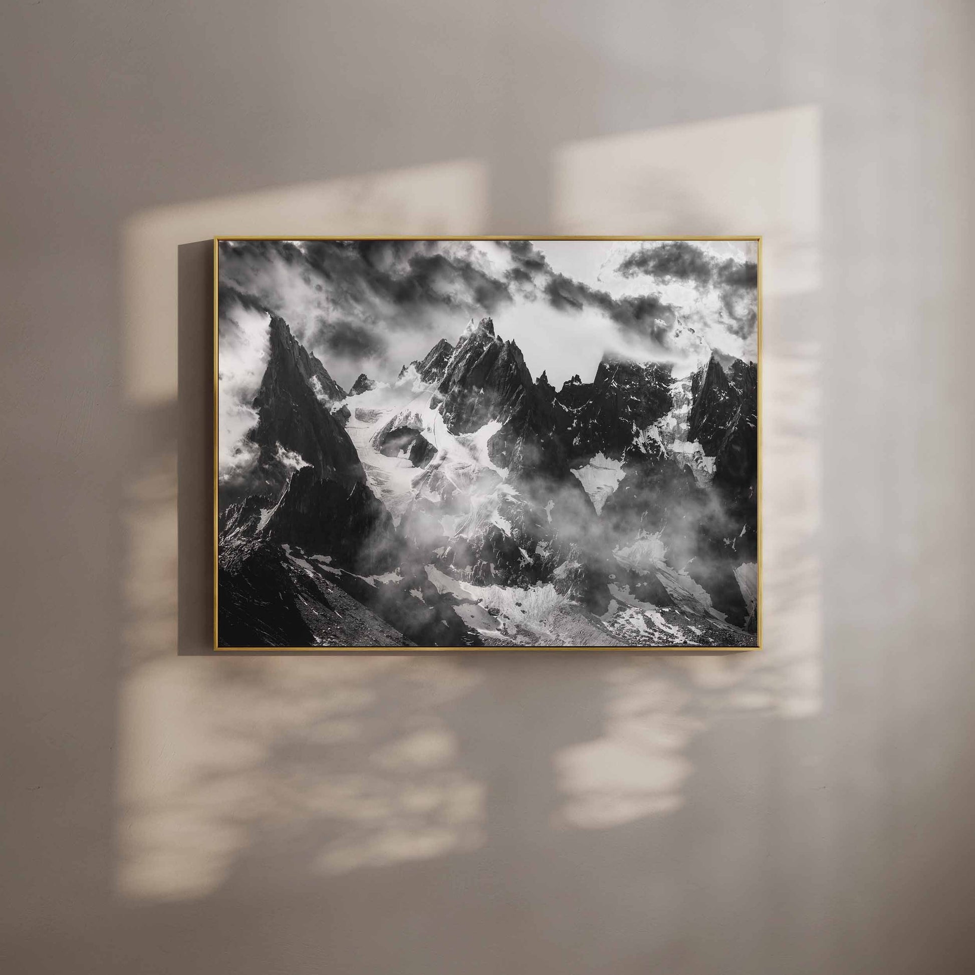 Black and white wall art of the Needles of Chamonix, showcasing dramatic alpine peaks shrouded in mist, displayed in a minimalist gold frame.