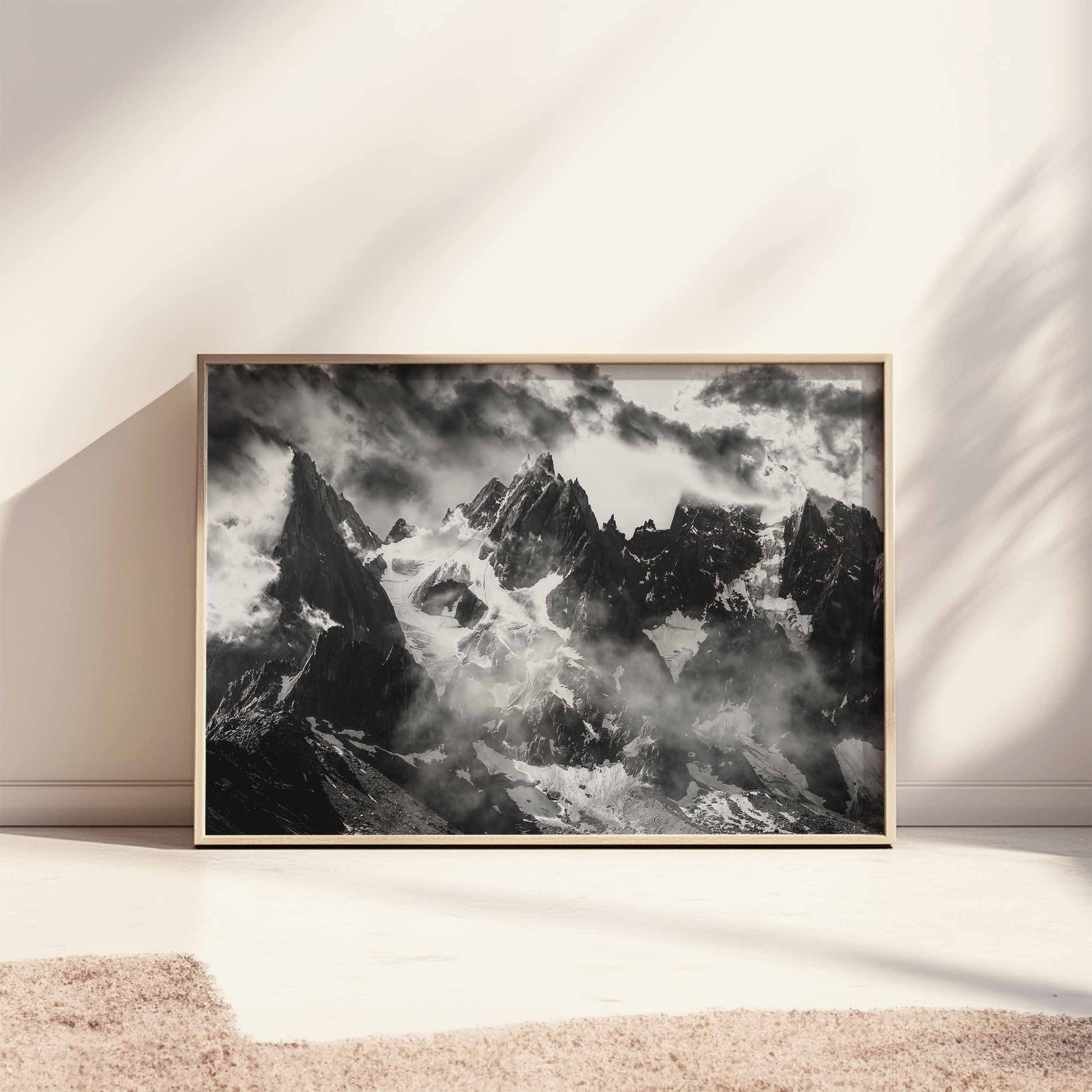 Horizontal black and white photography print of the Needles of Chamonix, leaning against a dark green wall, with dramatic lighting.