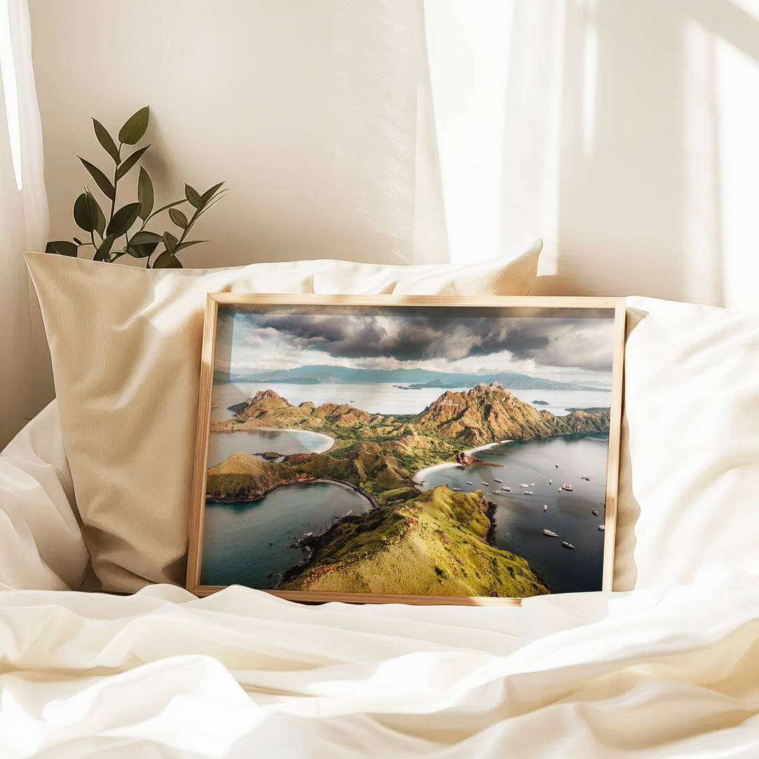 Natural wood framed Padar Island Komodo National Park Flores Indonesia aerial print leaning against pillows in a bedroom setting