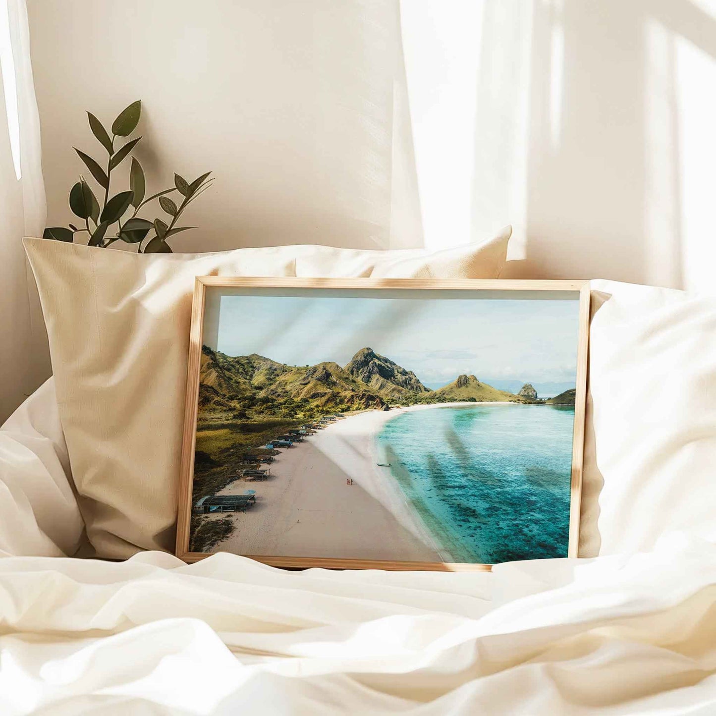 Pink Beach Padar Island Komodo National Park framed print in natural wood frame leaning against pillow on white bed