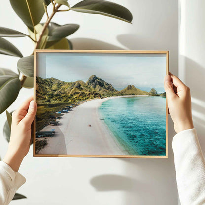 Hands holding Pink Beach Padar Island Komodo National Park framed wall art print in natural oak wood frame against white wall