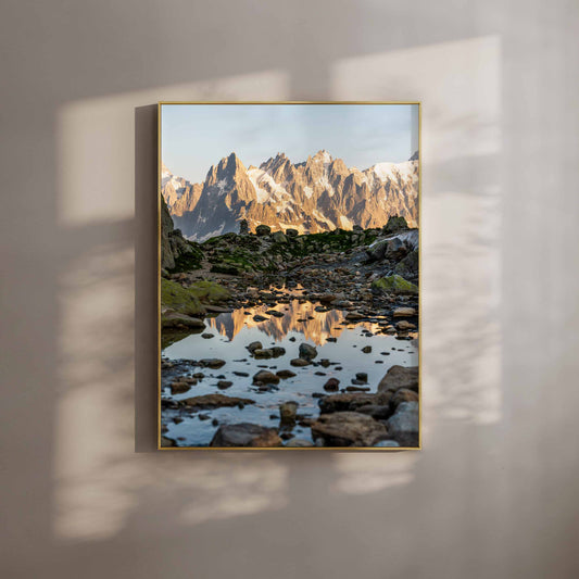 Reflection of the Aiguille de Chamonix captured at dawn with stunning alpine surroundings and rocky foreground.