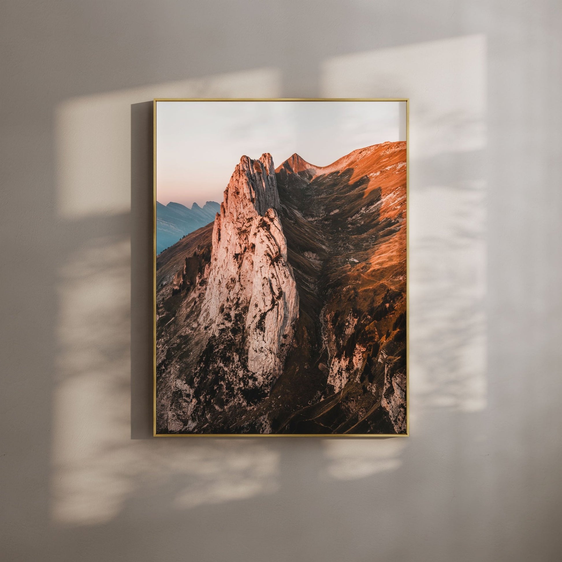 Sunrise view of Saxer Lucke, Switzerland in a gold frame, casting warm light on the beige wall.