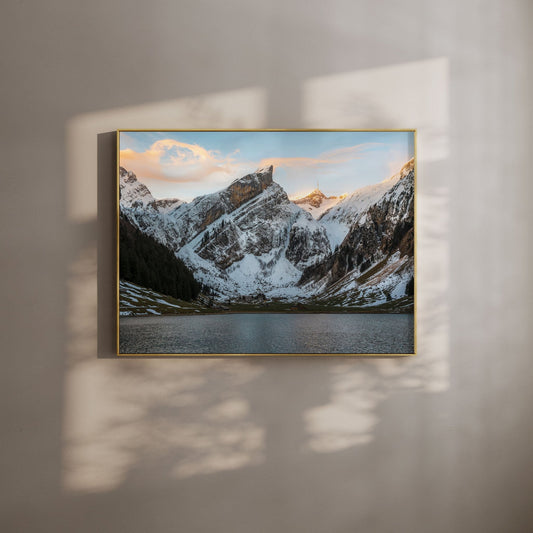 Snowy Seealpsee lake surrounded by alpine mountains in Appenzell, Switzerland, during sunset.