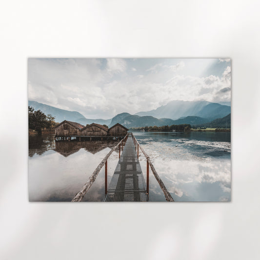 Sunrise light over calm Kochelsee water with alpine peaks and boathouses