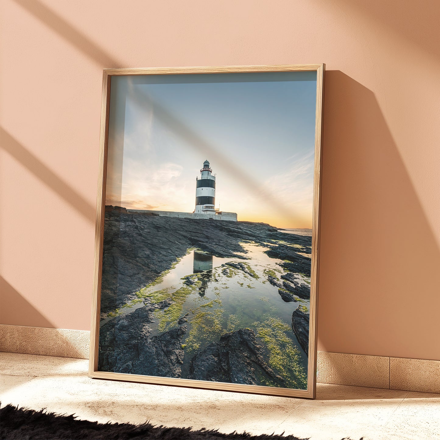 Framed Hook Head lighthouse print in soft peach room, sunset light casting shadows
