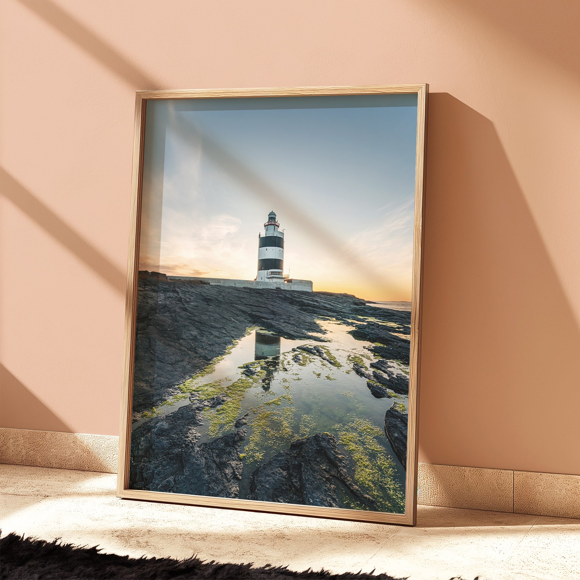 Framed Hook Head lighthouse print in soft peach room, sunset light casting shadows