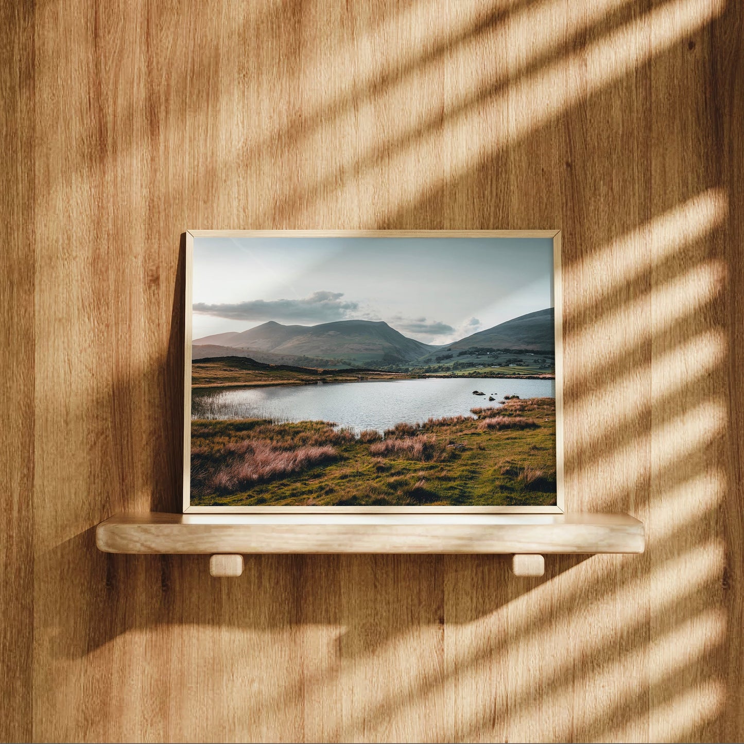 Landscape print of Tewet Tarn on wood shelf with dramatic light