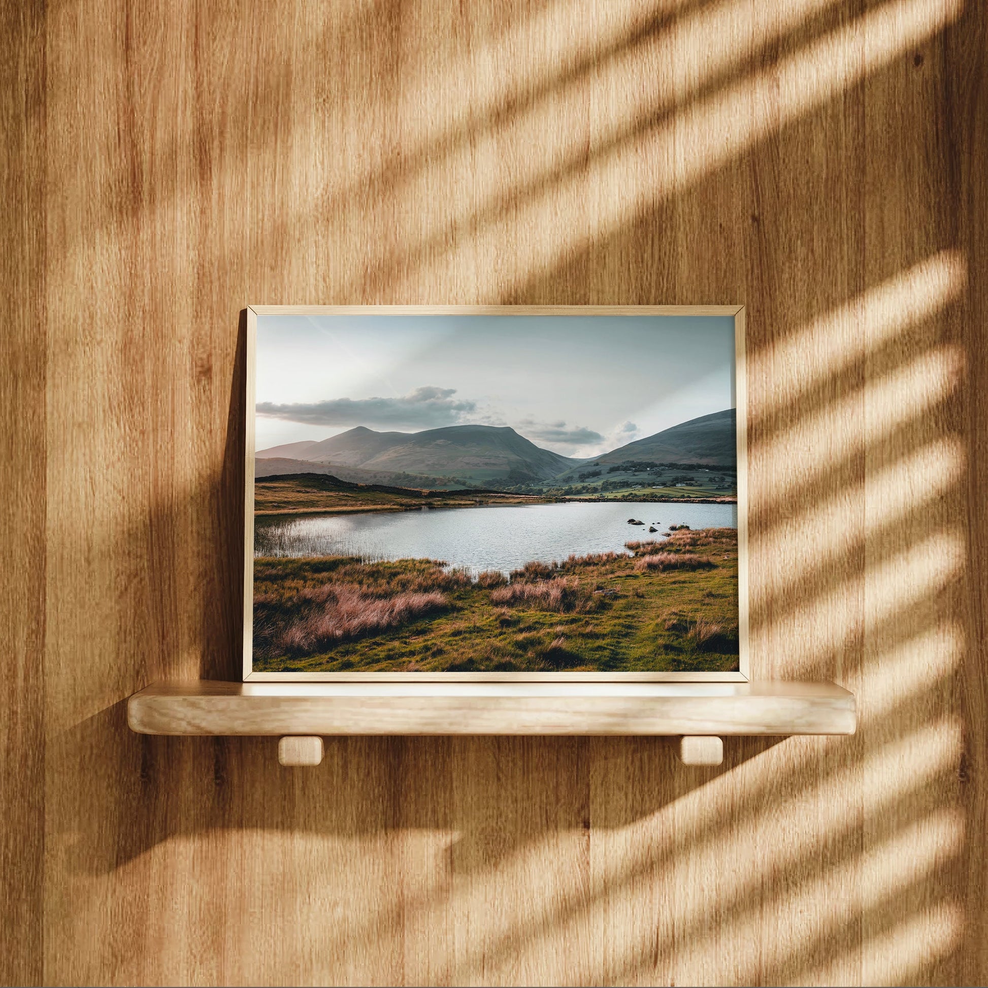 Landscape print of Tewet Tarn on wood shelf with dramatic light
