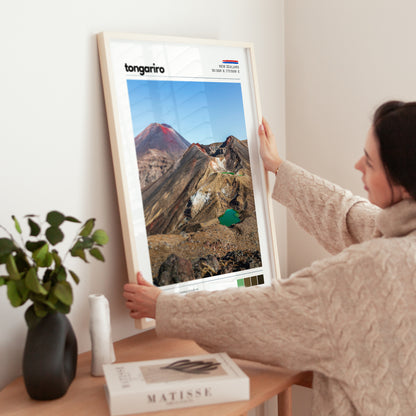 Person adjusting a framed Tongariro Crossing wall art print in a modern interior